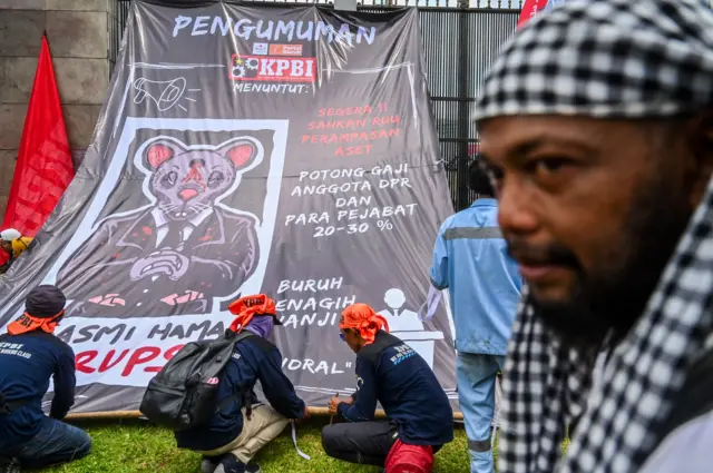 Sejumlah buruh memasang spanduk saat melakukan aksi di depan Kompleks Parlemen, Senayan, Jakarta, Kamis (28/8/2025). Dalam aksi tersebut mereka menuntut agar RUU Perampasan Aset dan berantas korupsi segera disahkan.