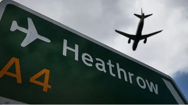 Самолет садится над дорожным знаком с указанием на Хитроу