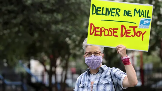 Mulher protestaafiliado vaidebetWashington com placa com os dizeres 'Entregue as correspondências / deponha DeJoy'