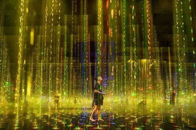 People walk through a large colourful art installation