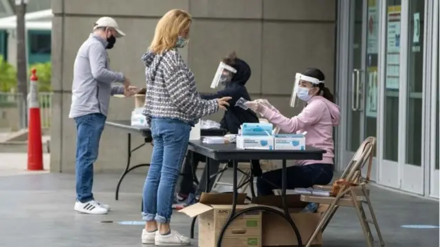 Polling center clerks assist voters outside the Staples Center as California in-person early voting for the U.S. Presidential election begins, in Los Angeles, California, USA, 24 October 2020.