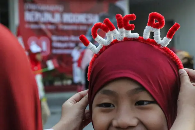 Seorang siswa menggunakan bando merah putih
