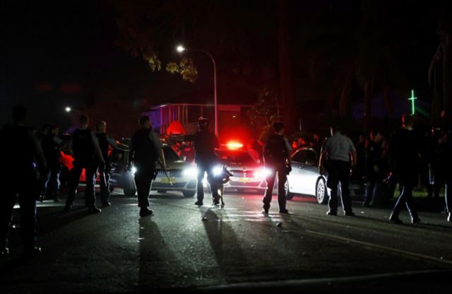 Policiais e carros de polícia em rua de Sydney durante a noite