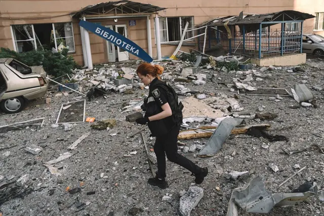 Bir kadın Polis memuru hasar gören bir binanın etrafında yürüyor