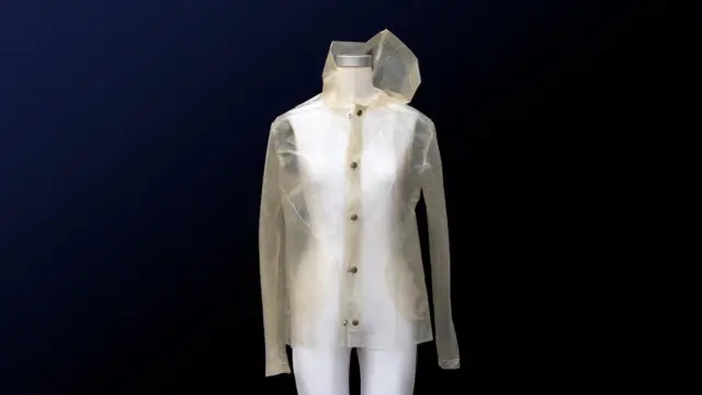 Beyaz bir mankene, sarı tonlu şeffaf bir yağmurluk giydirilmiş.