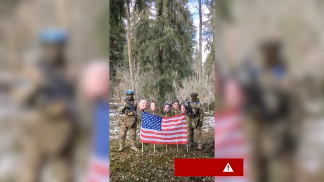 Кадр из постановочного видео, на котором изображены двое мужчин, одетых так, как будто они украинские солдаты, рядом с флагом США с изображениями Трампа, Маска и Джей Ди Вэнса на деревянных шестах