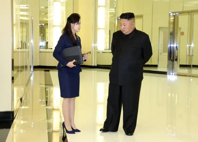 (캡션) 리설주 여사가 김정은 위원장의 서류 가방과 안경으로 보이는 것을 들고 있다