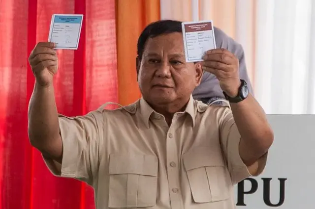 Presiden Indonesia Prabowo Subianto menunjukkan surat suara saat memberikan suara pada pemilihan daerah secara simultan di Bogor, Jawa Barat pada 27 November 2024.