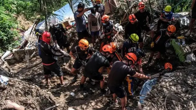 Emergency workers wear helmets dey try retrieve deadibody dem for landslide site