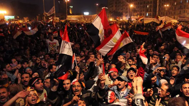 عدد من الأشخاص يحملون الأعلام المصرية ضمن ثورة 25 يناير/كانون الثاني 2011 في مصر.