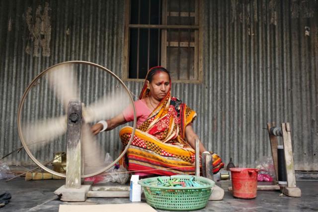 টাঙ্গাইল তাঁত পল্লিতে সুতা কাটছেন এক নারী। (ফাইল ছবি) 