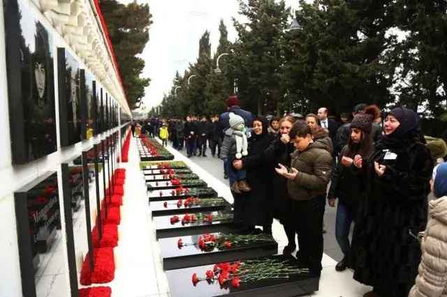 مردم جمهوری آذربایجان در مقابل دیوار یادبود کشته‌شدگان جمع شده‌اند و بر قبر آنها گل گذاشته‌اند