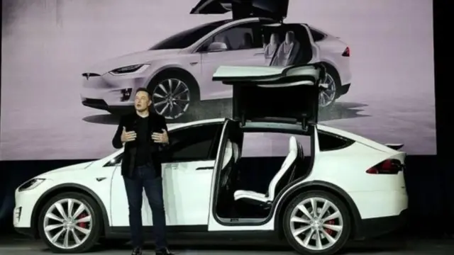 Musk gesticulando em frente a carro no palco