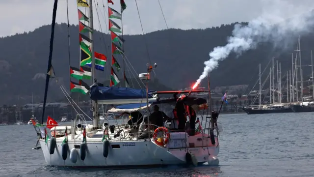 Activists on board a sailboat taking part in the Global Sumud Flotilla light flares as they depart from the port of Marmaris, southern Turkey (14 May 2026)