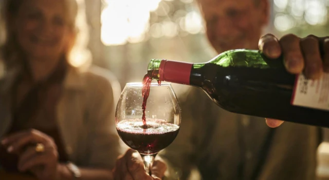 Şarap kadehi dolduran bir kişi