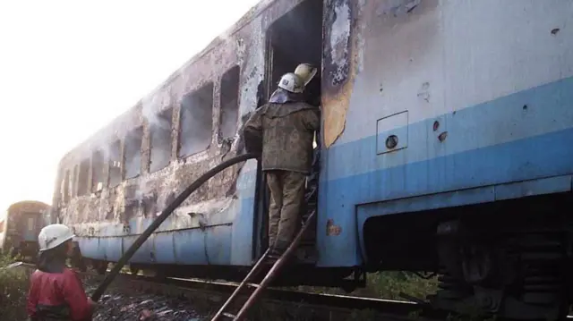Згорілий локомонтив, який загасили пожежні. Двоє з них стоять за сходах вагону. 
