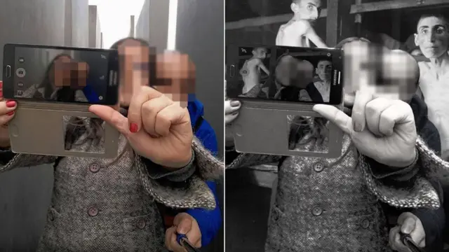 Dos mujeres tomándose una selfie en el memorial con las barracas de un campo de concentración de fondo.