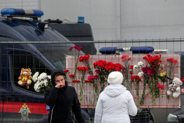 أشخاص يضعون الزهور قرب قاعة الحفلات الموسيقية المحروقة في أعقاب هجوم إرهابي في كراسنوجورسك، خارج موسكو
