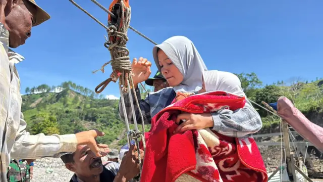 Khairunnisa bersama bayinya berusia 1,5 tahun bersiap untuk meluncur dengan seutas sling baja untuk mencari kebutuhan hariannya dari desa yang terisolir.