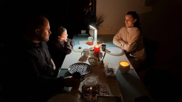 Родина сидить за столом у темряві