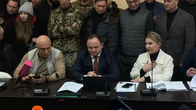 Юлія Тимошенко, її адвокат і чоловік сидять за столом в суді
