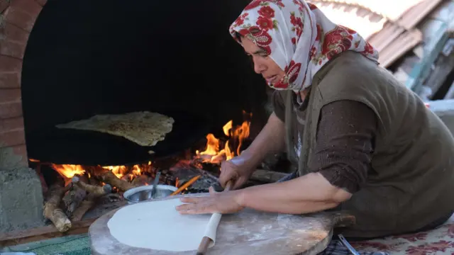 Mulher trabalhando na produção artesanal do pão turco conhecido como gözleme