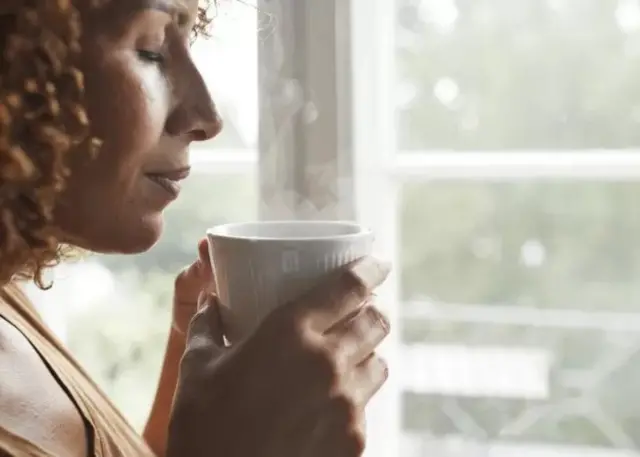 Une femme tenant une tasse de café