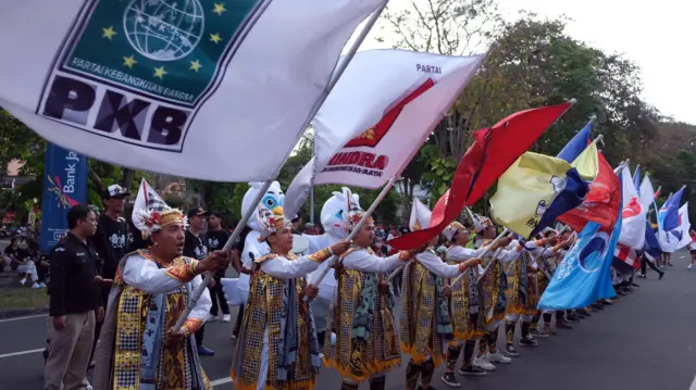 Sejumlah penari membawa bendera partai politik saat Kirab Pemilu Tahun 2024 di Denpasar, Bali, Minggu (06/08).