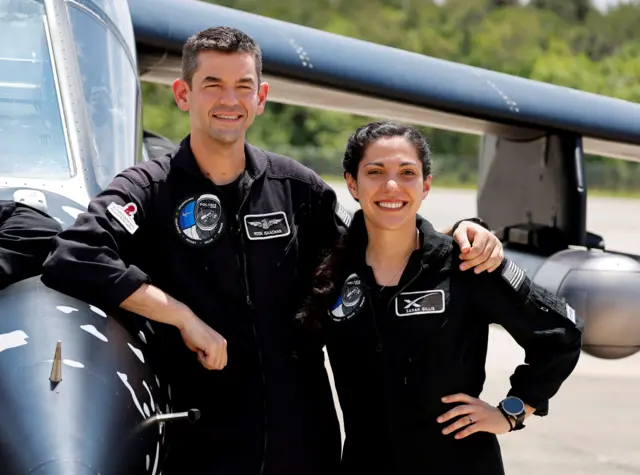 Jared Isaacman y Sarah Gillis posando junto a un avión.