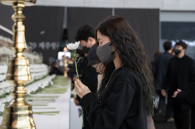 12.29 여객기 사고 희생자들을 기리는 합동 추모식에서 한 여성이 헌화를 하고 있다. 