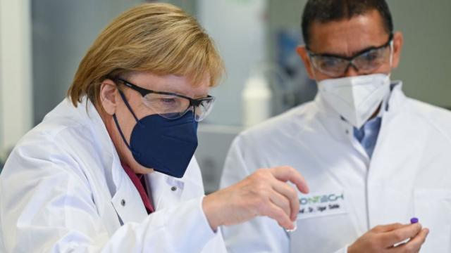 Ugur Sahin, founder and CEO of the biotechnology company BioNTech shows German Chancellor Angela Merkel dummy ampoules of the BioNTech/Pfizer COVID-19 vaccine during her visit to the BioNTech Vaccine Production Plant on August 19, 2021 in Marburg, Germany.