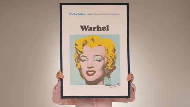 Una persona sujeta un cuadro de Warhol de Marilyn Monroe