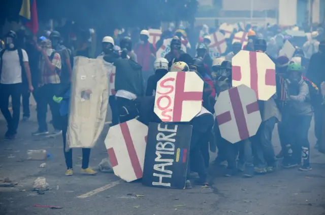 Los manifestantes de oposición aparecen pertrechados con máscaras y escudos.
