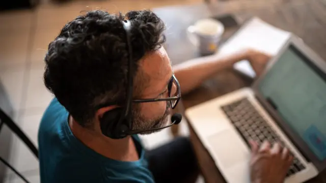 Homem trabalhandocodigo de bonus betano outubro 2024casacodigo de bonus betano outubro 2024frente ao laptop com fonecodigo de bonus betano outubro 2024ouvido