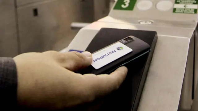 Mobile payment. A cell phone being used to pay for a metro train ticket. The handset is fitted with a smart card that allows near-field communication (NFC), a contactless technology that enables the handset to communicate with the ticket barrier