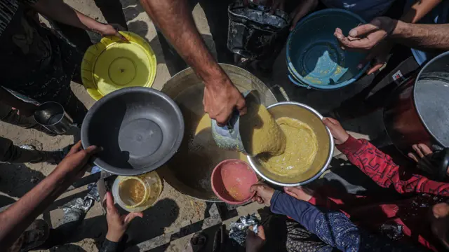 صورة تظهر عدداً من النازحين يمدون بأطباقهم للحصول على طعام في جباليا شمالي قطاع غزة.