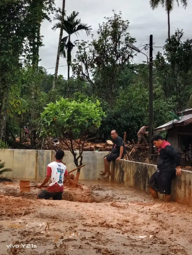 Proses penggalian di tanah berlumpur untuk menguburkan korban banjir di sisi bangunan Gereja HKBP Hutanabolon.