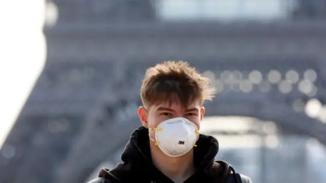 প্যারিসে আইফেল টাওয়ারের সামনে মুখোশ পরা একজন