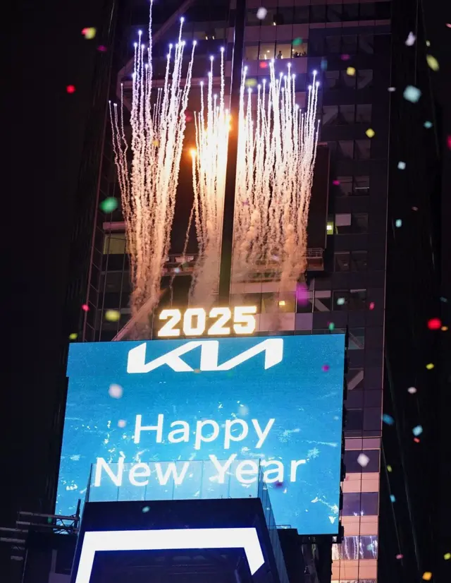 Un tablero electrónico muestra "Feliz Año Nuevo" con fuegos artificiales