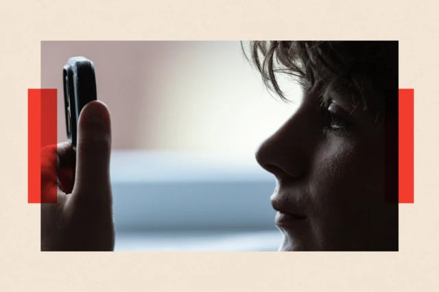 Un jeune garçon regarde attentivement l'écran d'un téléphone