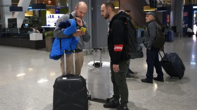 Dois homens brancos com malas conversampagbet codigo promocionaluma áreapagbet codigo promocionaldesembarquepagbet codigo promocionalaeroporto