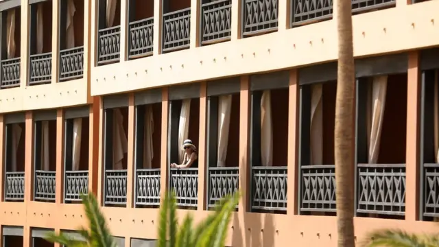 A quarantined tourist looks out from a hotel balcony