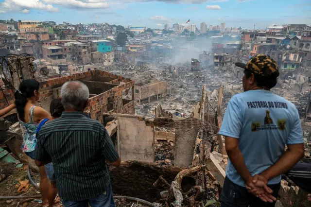 Residents look at the remains of Educandos neighbourhood the day after it was ravaged by a massive fire, in Manaus, Amazonas state, Brazil