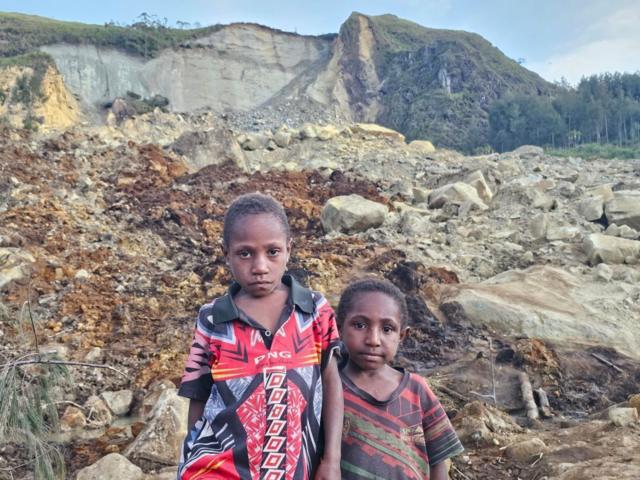 Dos niños posan ante la cámara de fotos en la zona del deslizamiento de tierra en Papúa Nueva Guinea.