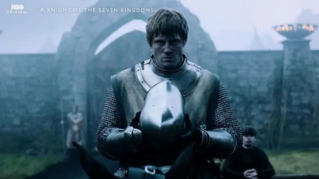 Bir diziden posterde, bir orta çağ şövalyesi elinde miğfer tutuyor ve sert şekilde kameraya bakıyor. Arkada bir kale var.