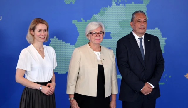 İki kadın ve bir erkek bir haritanın önünde poz veriyor.