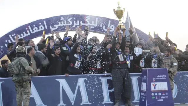 یکی از اعضای تیم بزکشی ولایت سرپل جام قهرمانی را بالای سر برده است.