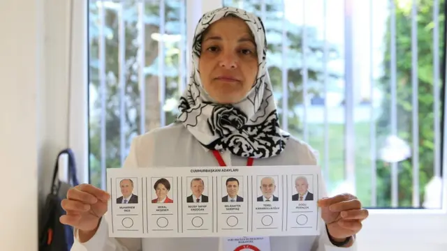 One returning officer shows a voting paper for the Presidential and General elections in Turkey, at a polling station at Turkey Consulate-General in Berlin on June 07