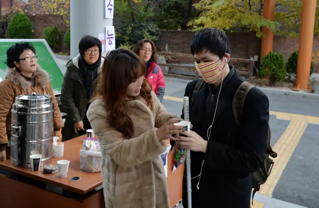 과거 수능 현장. 서울 종로구 신교동 서울맹학교에서 학부모들이 시각장애 수험생에게 커피 등 간식을 나눠주고 있다