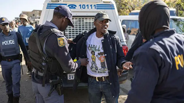 Police hold man wey wear cap